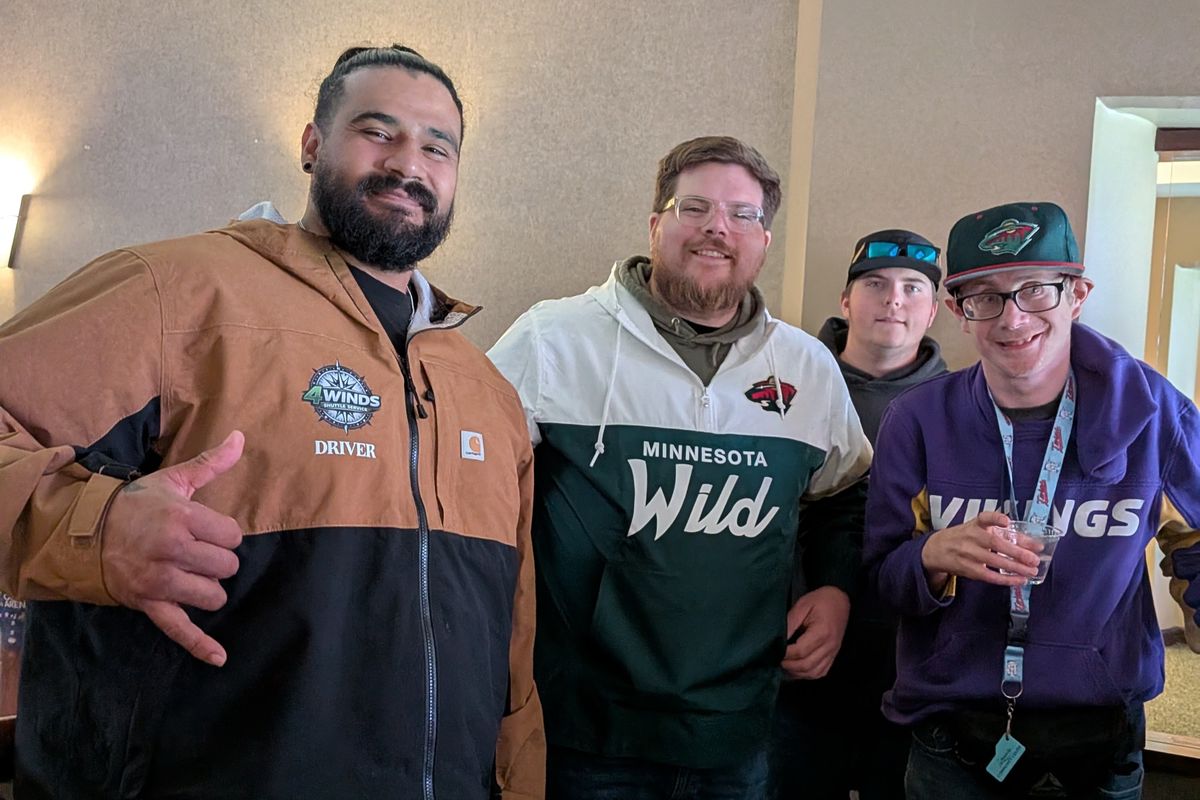 Four friends posing in the suite, one throwing a shaka