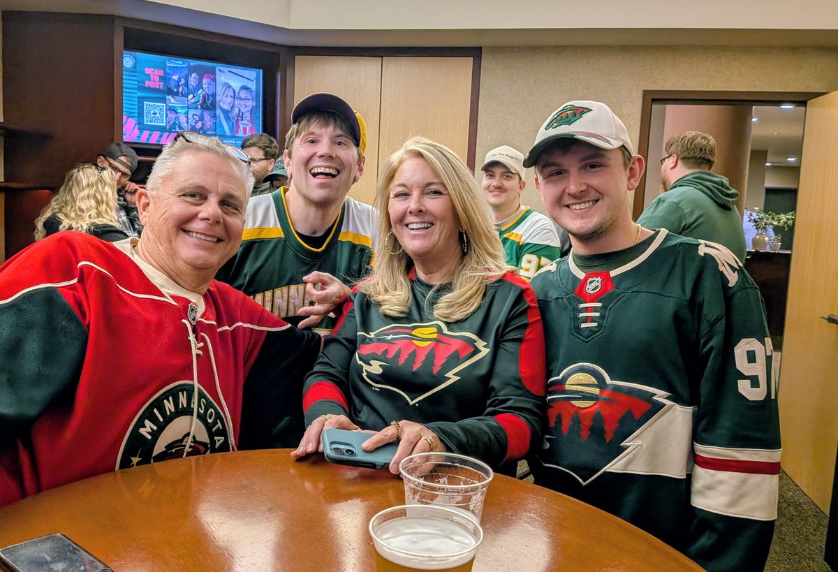 Friends in Wild jerseys smiling together around a table in the suite